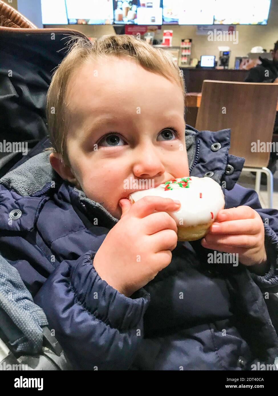 Kleiner Junge essen Tasse Kuchen tragen Jacke Stockfoto