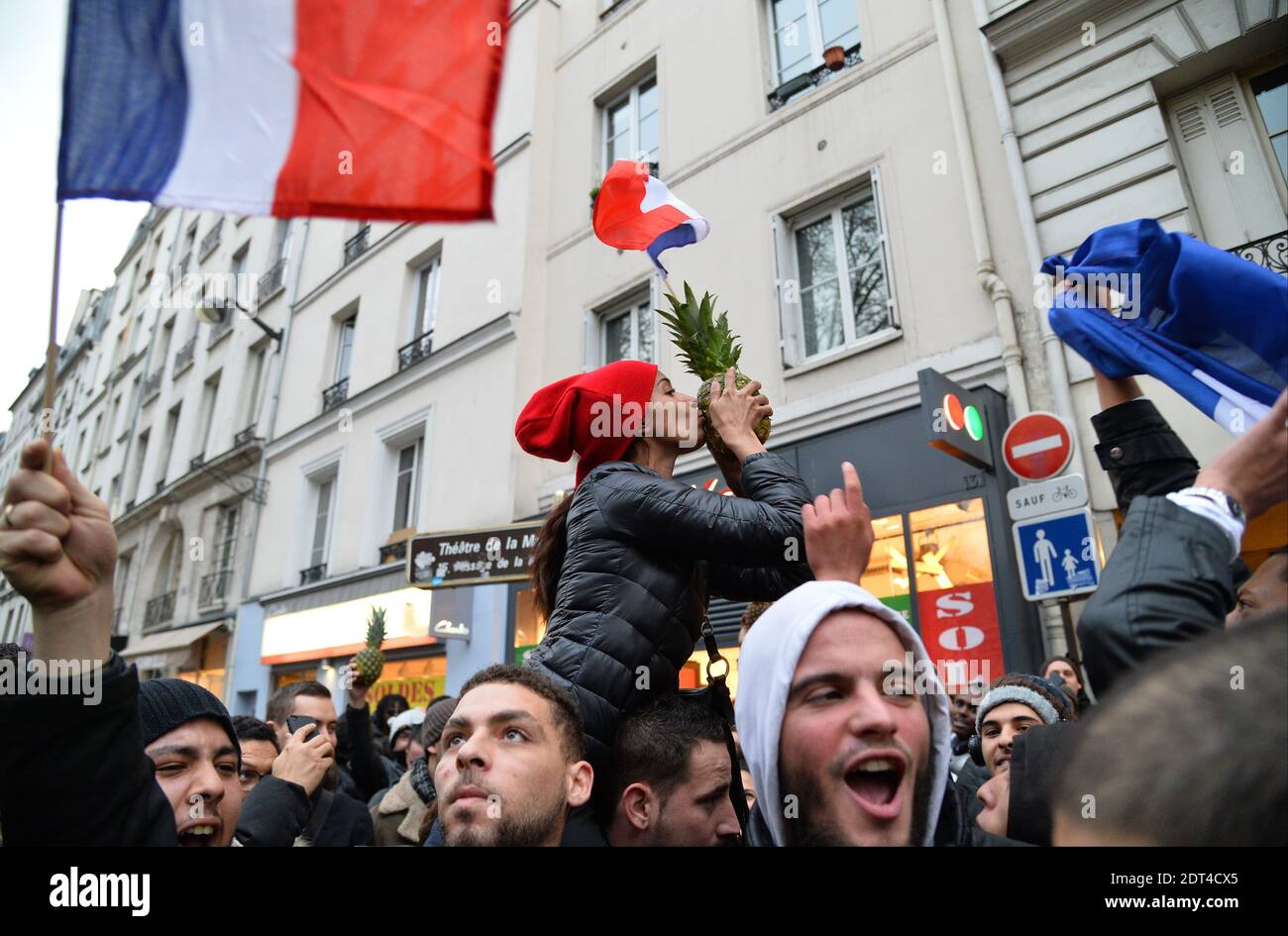 Fans des französischen Comics Dieudonne M'Bala M'Bala treffen sich in der Nähe eines Pariser Theaters, als einer von ihnen am 11. Januar 2014 in Paris die französische Nationalflagge schwingt und eine Ananas hält. Dieudonne wurde wiederholt wegen Anstiftung zu Rassenhass oder Antisemitismus verurteilt und hat zugestimmt, eine umstrittene Show aufzugeben, die in mehreren Städten verboten wurde. Nachdem eine Pariser Show heute von den Behörden verboten wurde, sagte er einer Pressekonferenz, dass er die "Le Mur" Show nicht mehr machen werde, sondern sie durch eine neue Performance ersetzen werde. Der Comic wurde im vergangenen Herbst für die Verwendung des Wortes "Shoanana verurteilt Stockfoto