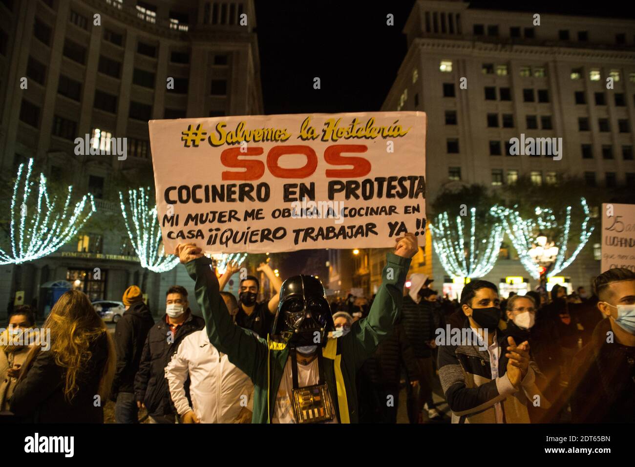 Barcelona, Katalonien, Spanien. Dezember 2020. Protestler mit einer Maske des Charakters Darth Vader, aus Star Wars, wird mit einem Banner, das sagt gesehen, Lasst uns die Gastfreundschaft SOS Koch aus Protest zu retten, meine Frau zwingt mich zu Hause kochen, Ich möchte jetzt arbeiten!.rund 800 katalanische Geschäftsleute und Arbeiter von Bars und Restaurants haben sich am Nachmittag des 21. Dezember in Barcelona konzentriert, um gegen die Beschränkungen zu protestieren, die die Regierung wegen Covid-19 nach der Beschränkung der Öffnung in der Nacht angewandt hat. Quelle: Thiago Prudencio/DAX/ZUMA Wire/Alamy Live News Stockfoto