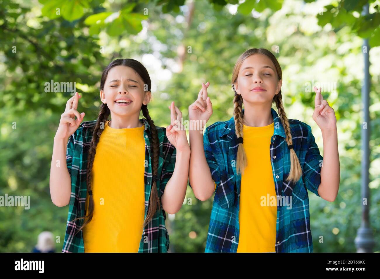 Happy kleine Mädchen mit Schönheit Look in lässigen Mode-Stil halten die Daumen gekreuzt Sommer im Freien, machen Wunsch. Stockfoto