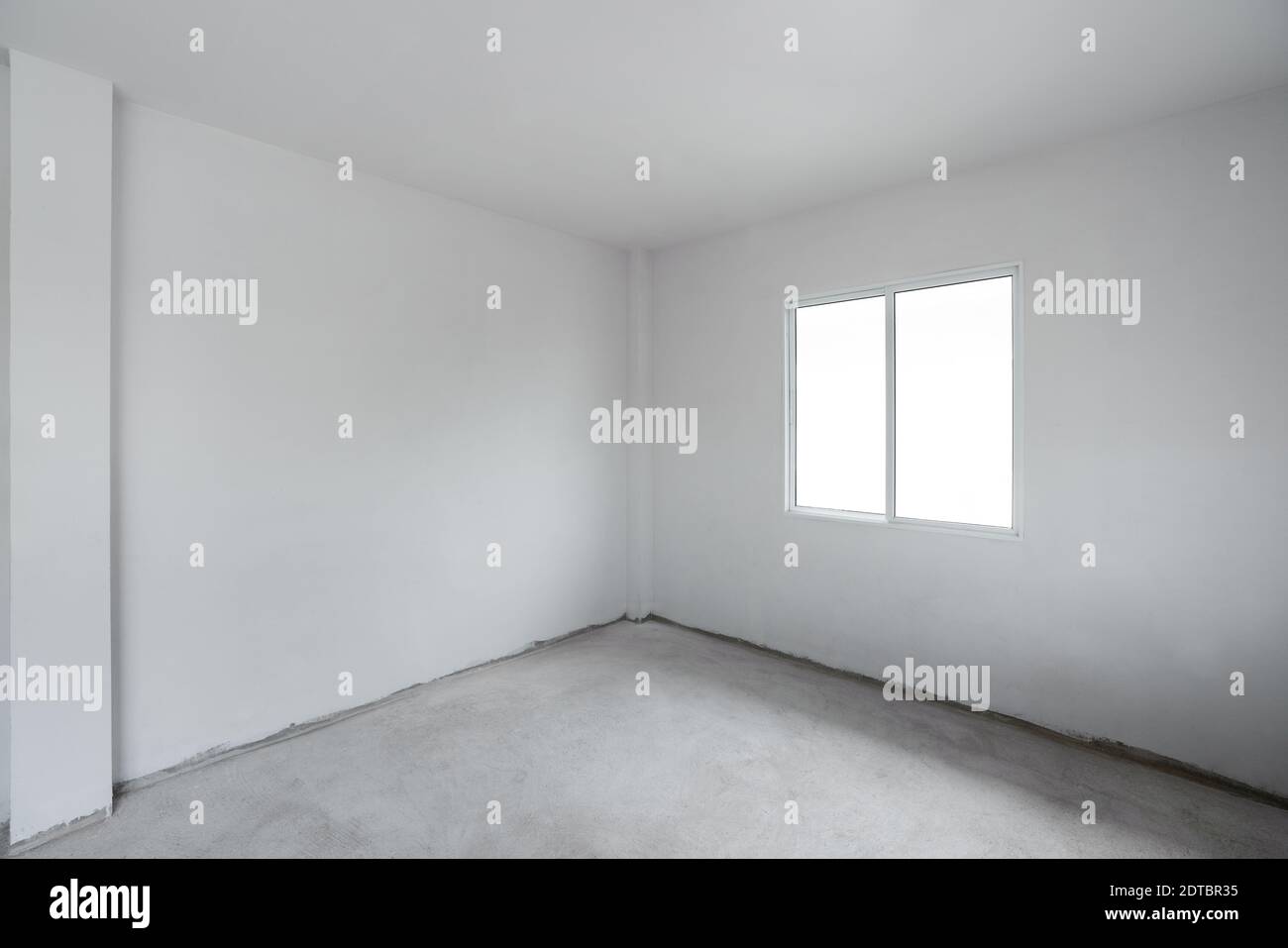 Betonzementboden mit weißer Wand und Fenster. Im Bau leeres Zimmer innen Stockfoto