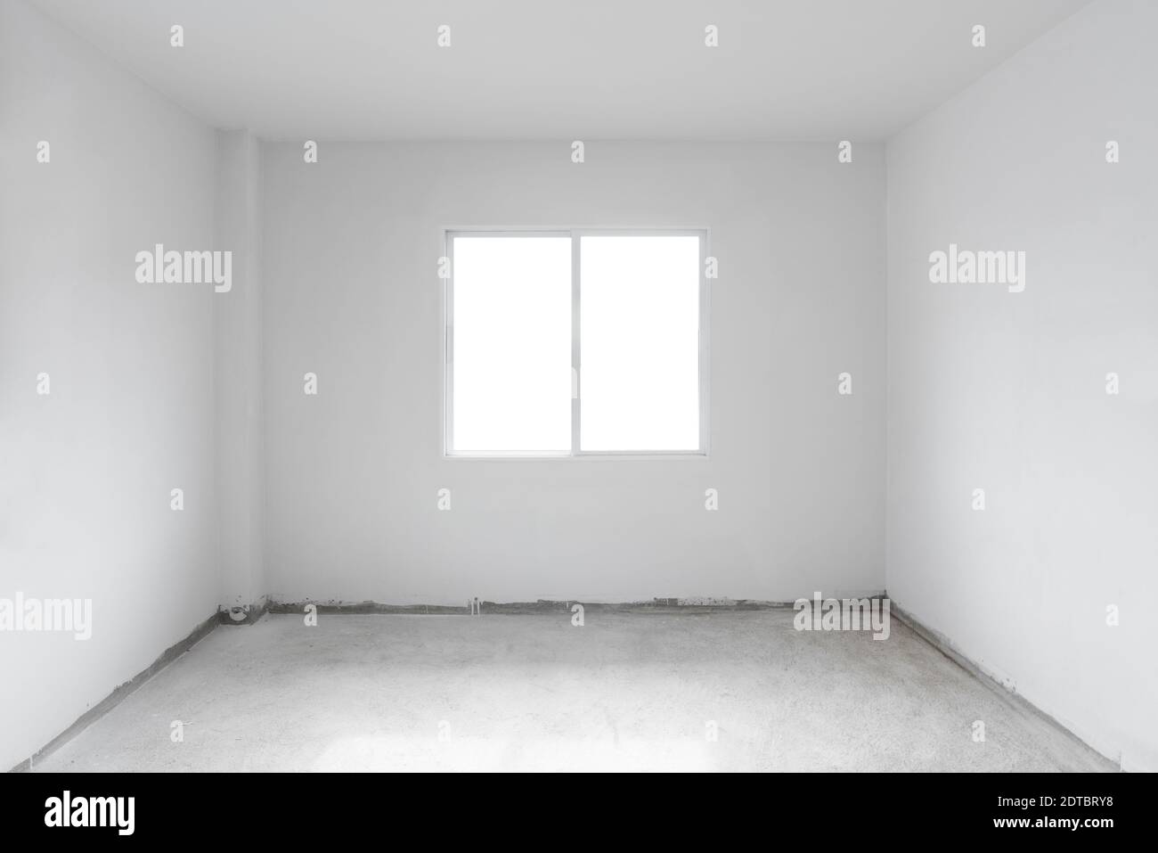 Betonzementboden mit weißer Wand und Fenster. Im Bau leeres Zimmer innen Stockfoto