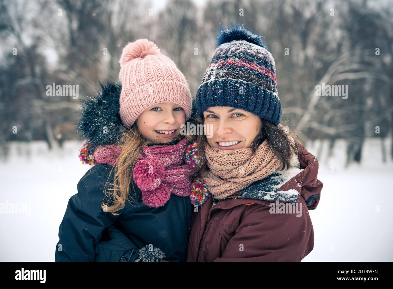 Kleines Mädchen und ihre Mutter spielen draußen am Wintertag. Aktives Winterurlaub Konzept. Stockfoto