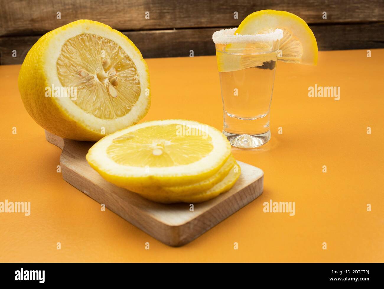 Tequila mit Zitrone und Salz auf einem hölzernen orangen Hintergrund Stockfoto