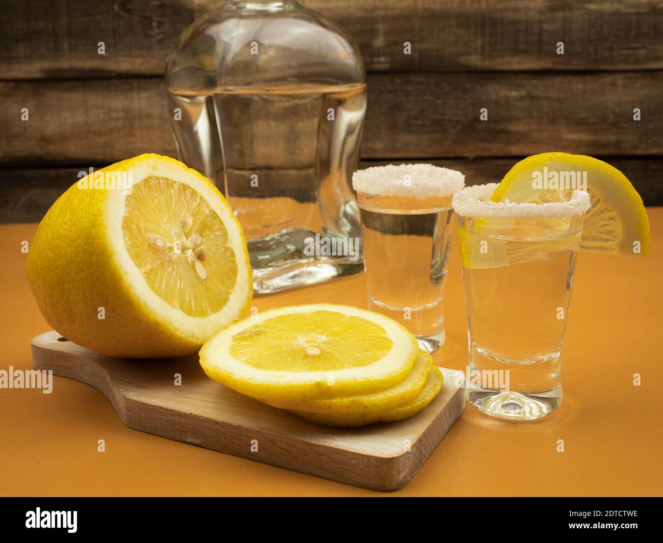 Tequila mit Zitrone und Salz auf einem hölzernen orangen Hintergrund Stockfoto