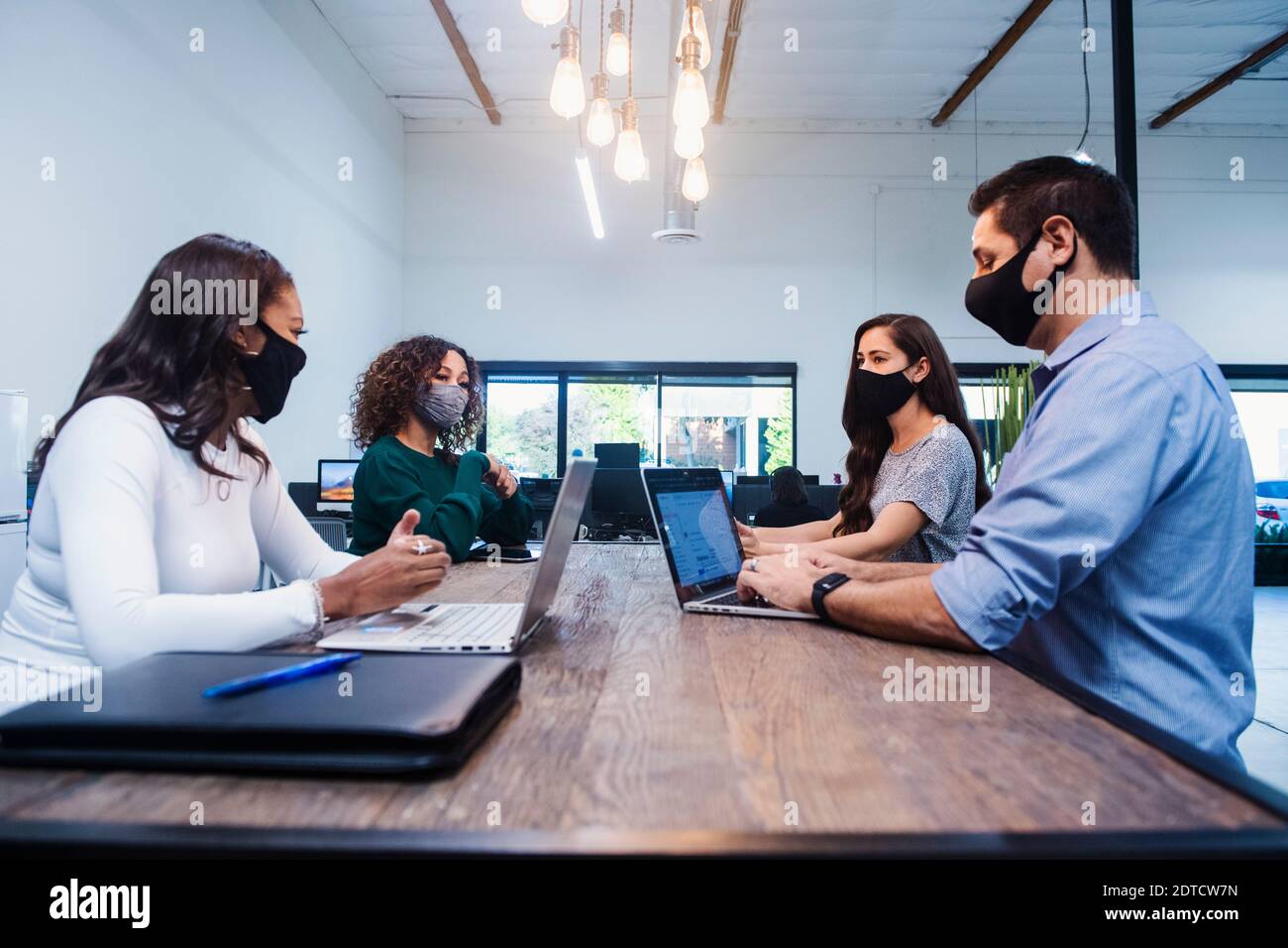 Menschen in Gesichtsmasken, die sich im Büro treffen Stockfoto