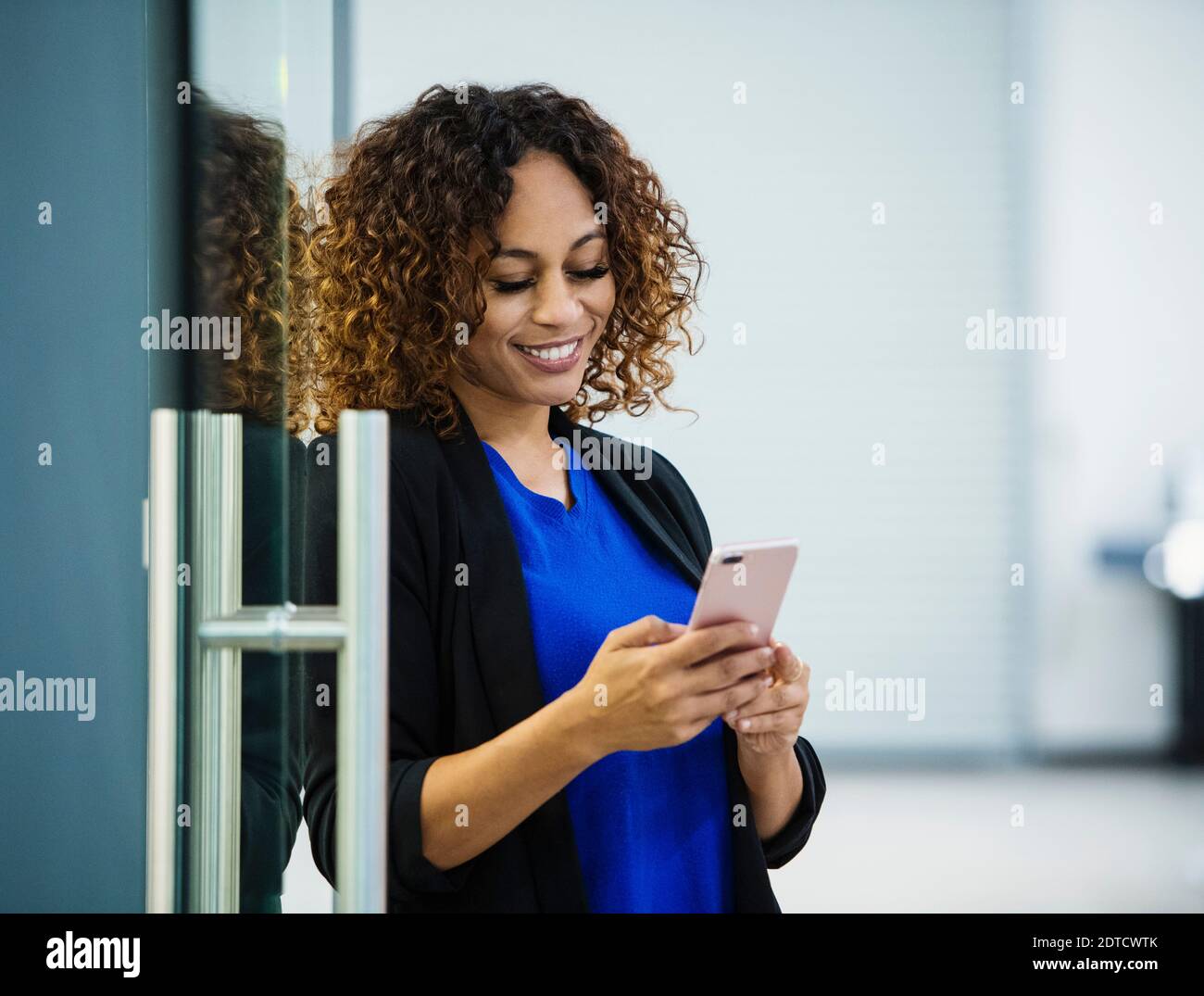 Lächelnde Geschäftsfrau mit Smartphone im Büro Stockfoto