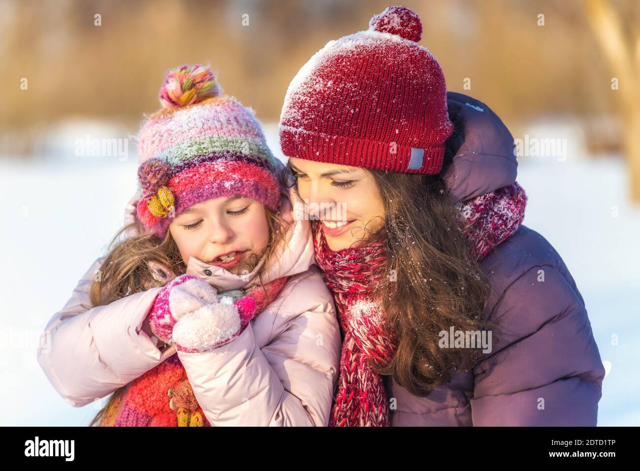 Kleines Mädchen und ihre Mutter spielen draußen an sonnigen Wintertag. Aktives Winterurlaub Konzept. Stockfoto
