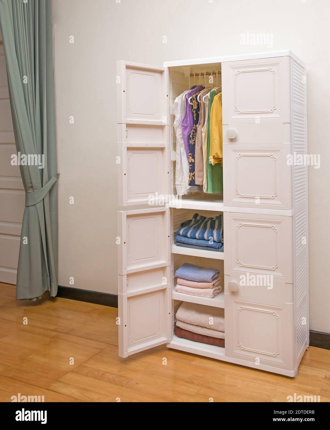 Offener Kunststoff-Kleiderschrank mit Kleidung im Schlafzimmer Hintergrund Stockfoto