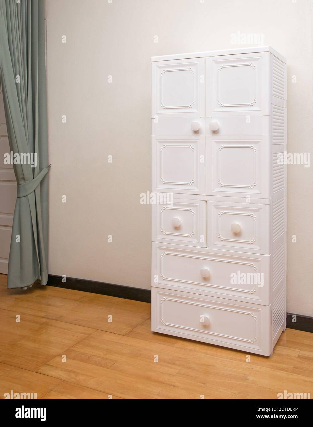Weißer Kunststoffschrank mit Schubladen auf Holzboden im Schlafzimmer Stockfoto
