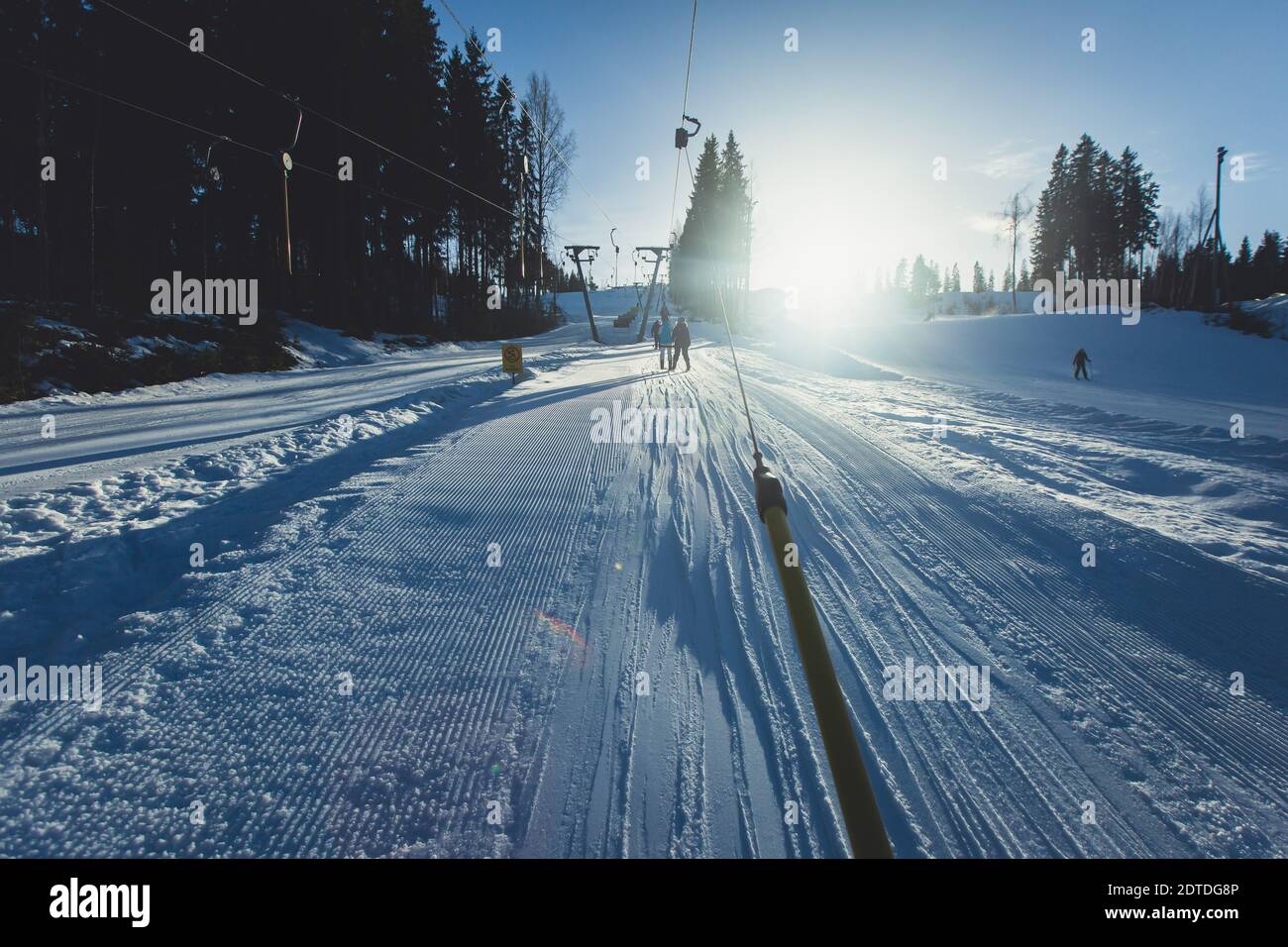 Schöne kalte Aussicht auf die Berge des Skigebiets, sonniger Wintertag mit Piste, Piste und Skilift, mit einer Gruppe von Bergabfahrtsskiern und Snowboardern Stockfoto