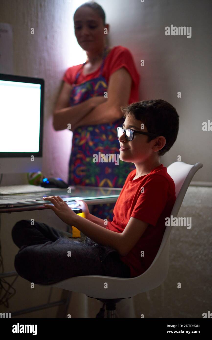 Mutter beobachten Sohn (8-9) während e-Learning zu Hause wegen Covid-19-Sperre Stockfoto