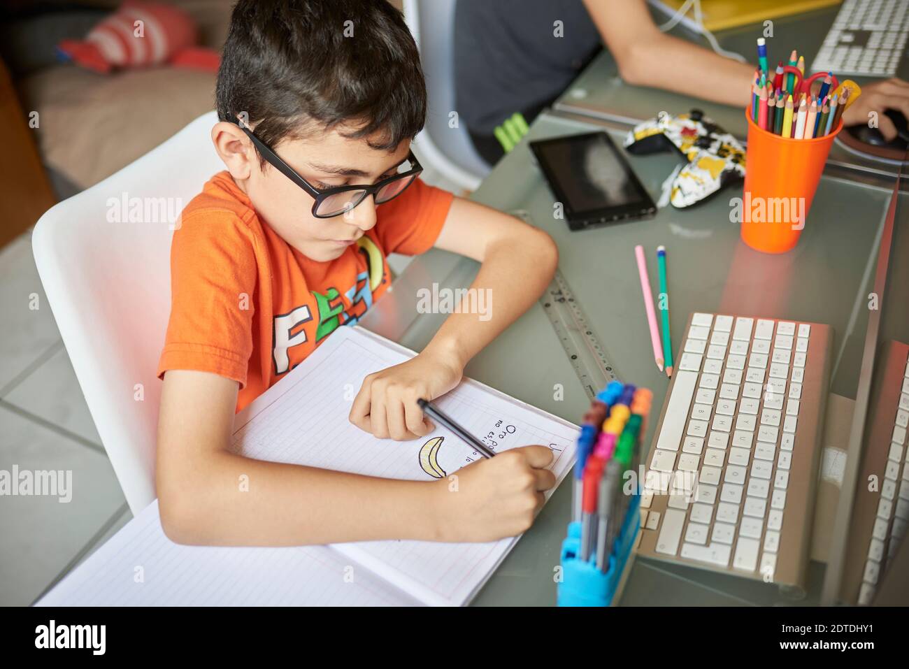 Zwei Jungen (8-9, 14-15), die während der Covid-19-Sperre am Schreibtisch zu Hause lernen Stockfoto