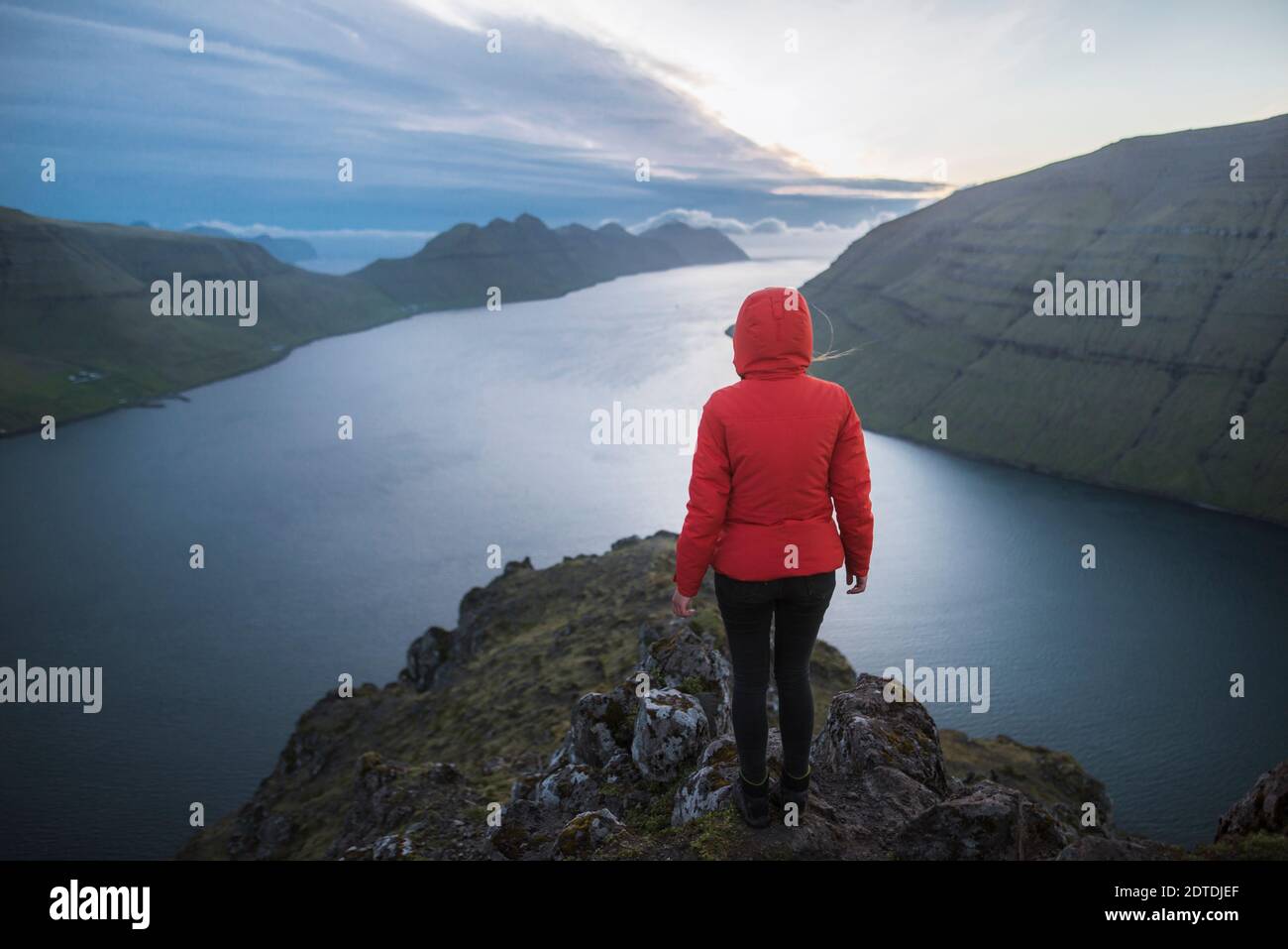 Dänemark, Färöer, Klaksvik, Frau, die auf dem Klakkur Berg über dem Meer steht und die Aussicht betrachtet Stockfoto