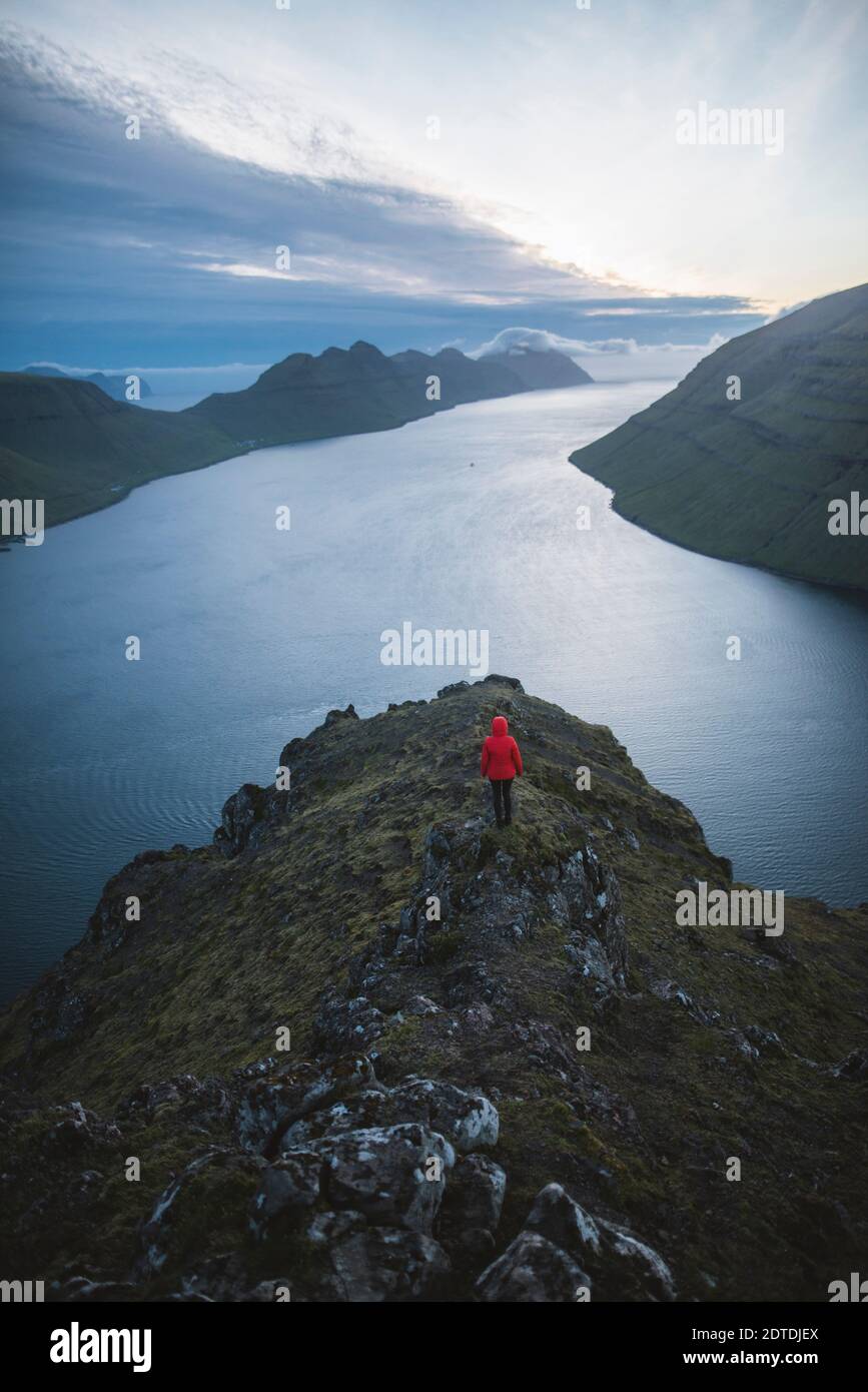 Dänemark, Färöer, Klaksvik, Frau, die auf dem Klakkur Berg über dem Meer steht und die Aussicht betrachtet Stockfoto