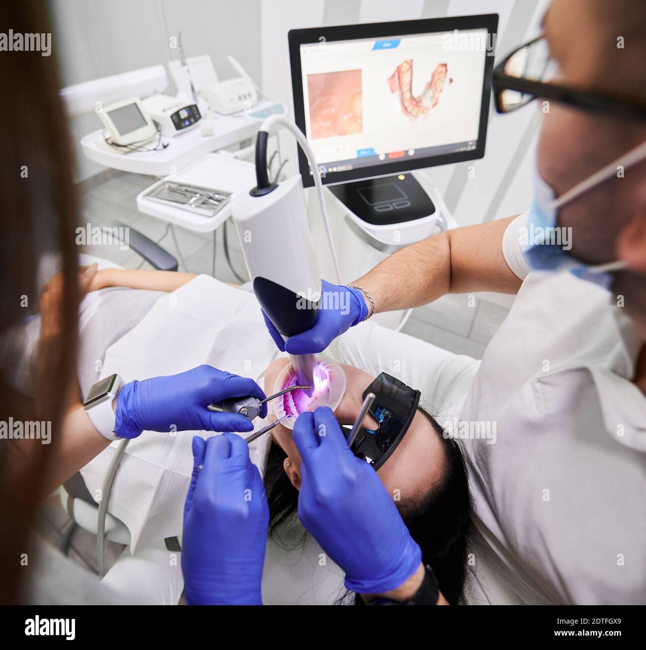 Zahnarzt und Assistent mit intraoralem Scanner bei der Untersuchung der Zähne des Patienten in der Zahnarztpraxis. Zahnärztlicher Spezialist für intraorales Scannen mit moderner Scanmaschine. Konzept der digitalen Zahnmedizin Stockfoto