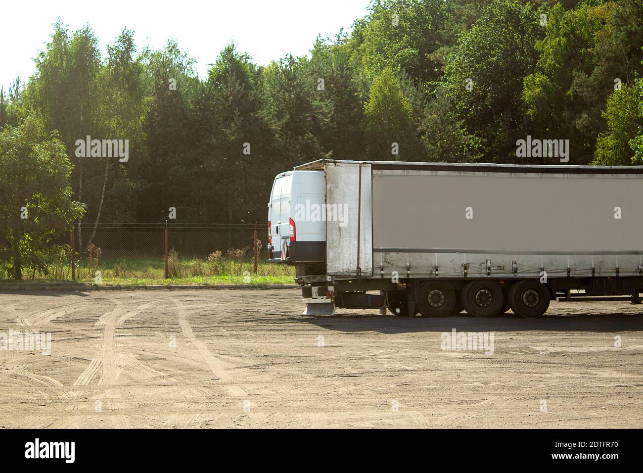 Auto in einem LKW-Anhänger. Ein großer LKW trägt ein kleines Auto in einem Anhänger Stockfoto