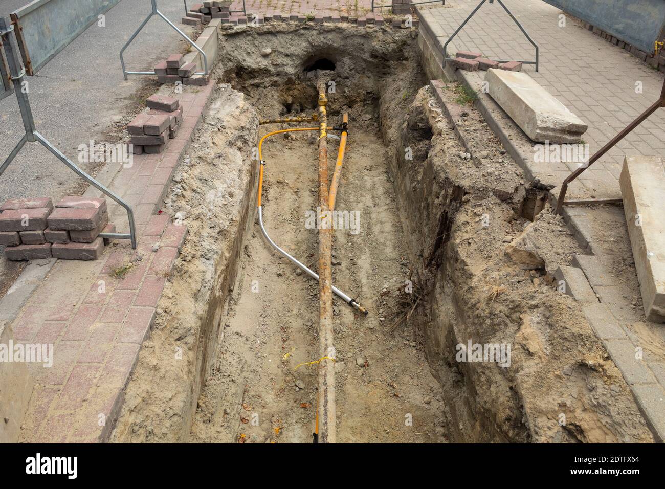 Eingezäunter Graben mit unterirdischen Versorgungseinrichtungen. Reparatur der Gaspipeline auf einer Stadtstraße, Anbindung der Gaspipeline Stockfoto