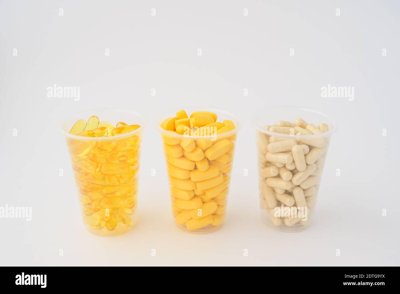 Drei Plastikbecher mit Pillen Softgels Omega3 Kapsel Vitamine Tabletten Auf weißem Hintergrund mit Copyspace Stockfoto