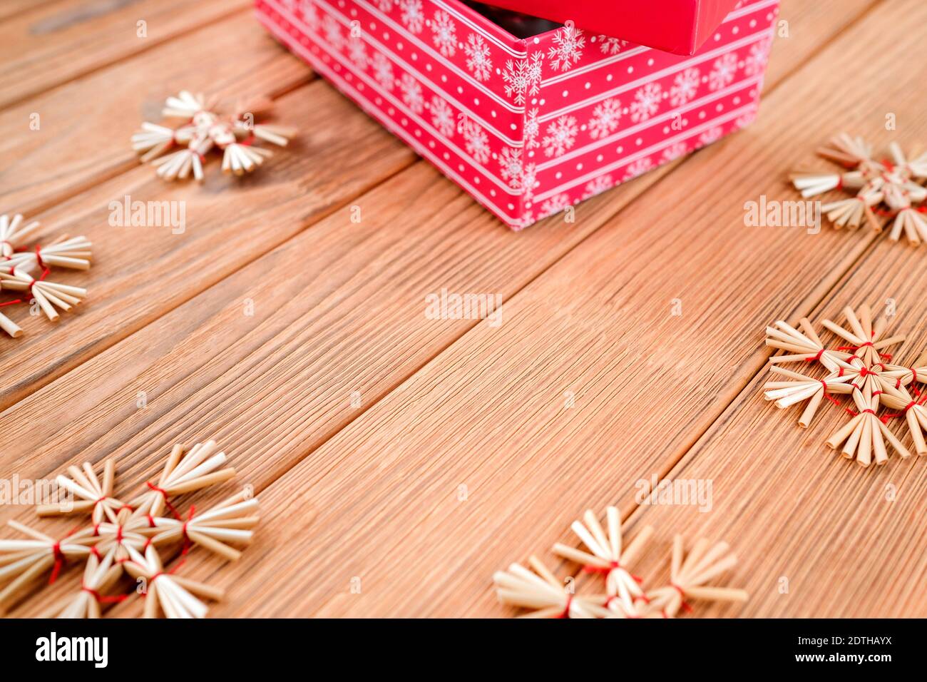 Neujahrskarte auf Holzhintergrund. Rotes Feld. Stroh Spielzeug Schneeflocken. Stockfoto Neujahrskarte auf Holzhintergrund. Rotes Feld. Stroh Spielzeug Schneeflocken. Stockfoto