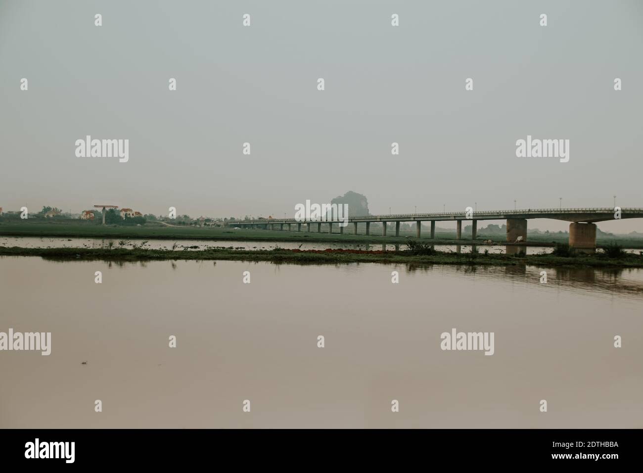Filmische dunkle und stimmungsvolle Landschaft einer Brücke über den Fluss in Ninh Binh, Vietnam Stockfoto