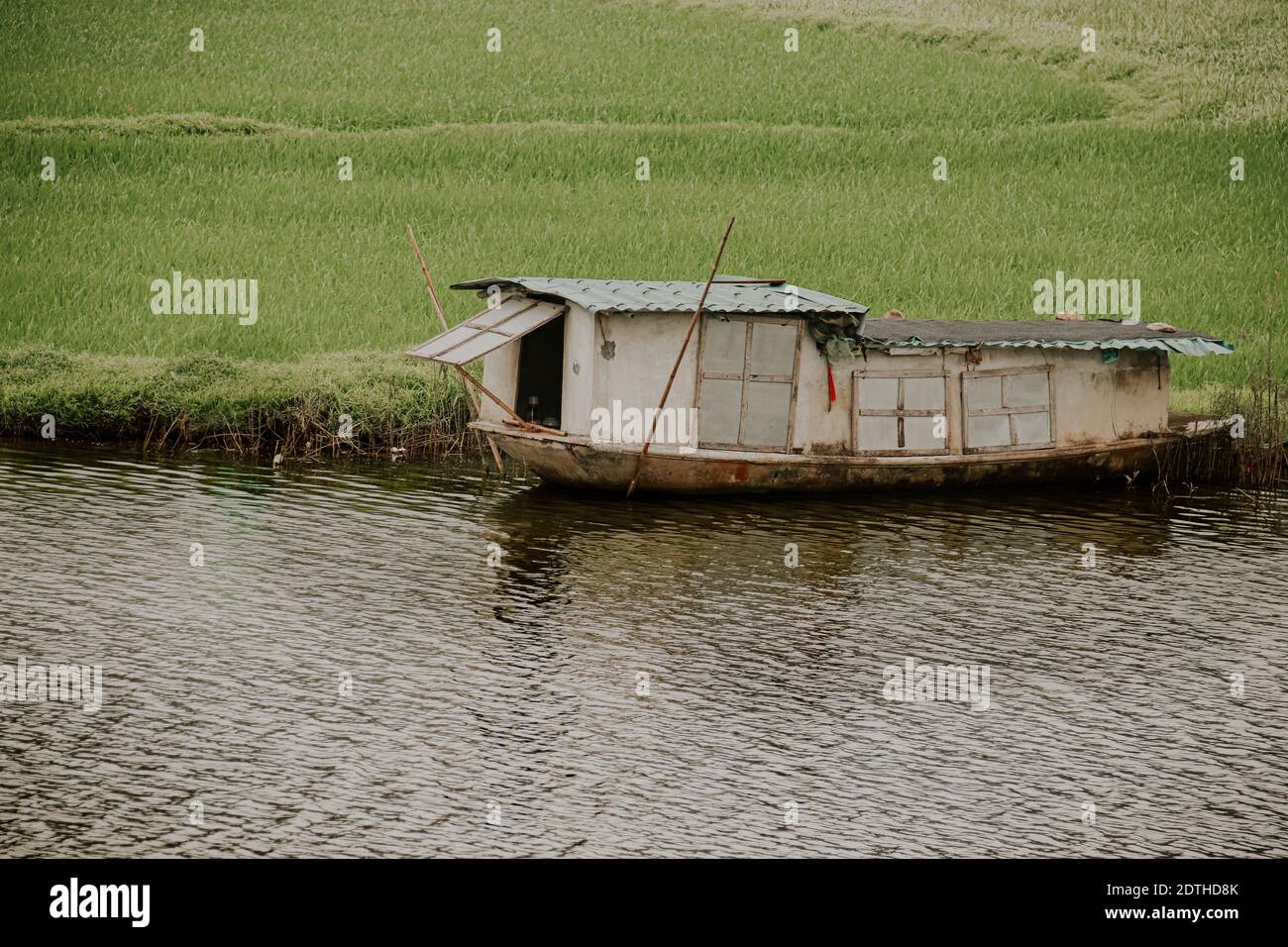Filmische Kulisse eines hölzernen Bootshauses, das am Flussufer von Ninh Binh, Vietnam, festgemacht ist Stockfoto