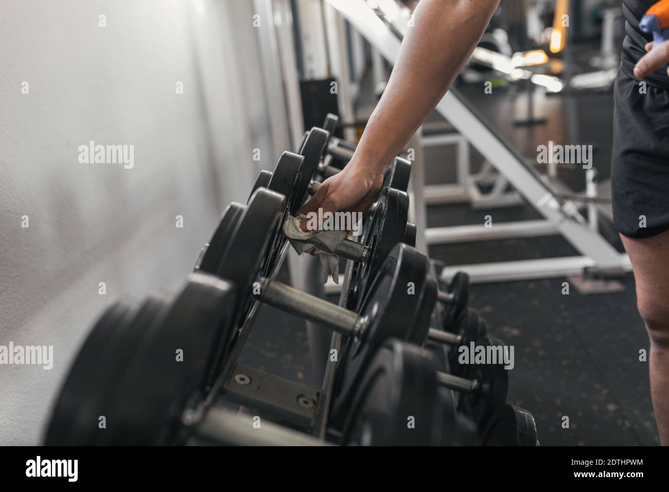 Nahaufnahme eines Sportlers mit Schutzhandschuhen und desinfizierenden Handgewichten im Health Club. Stockfoto