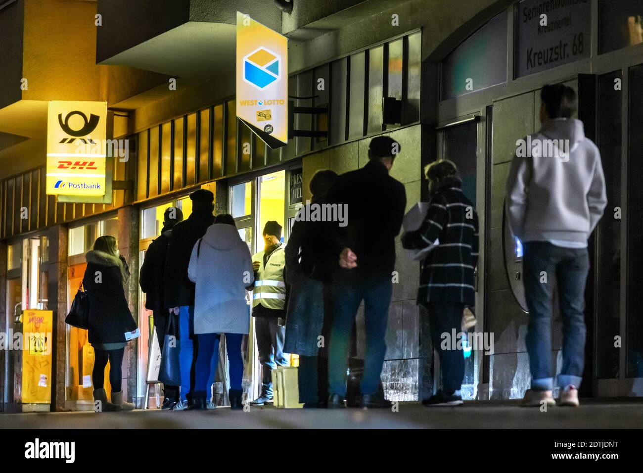 Dortmund, 18. Dezember 2020: Kunden warten auf dem Bürgersteig vor einer Filiale der Deutschen Post / DHL in Dortmund. Aufgrund der Einschränkungen der zweiten Sperrung der Corona-Pandemie dürfen nur 3 Kunden gleichzeitig in dieser Filiale bleiben. Stockfoto