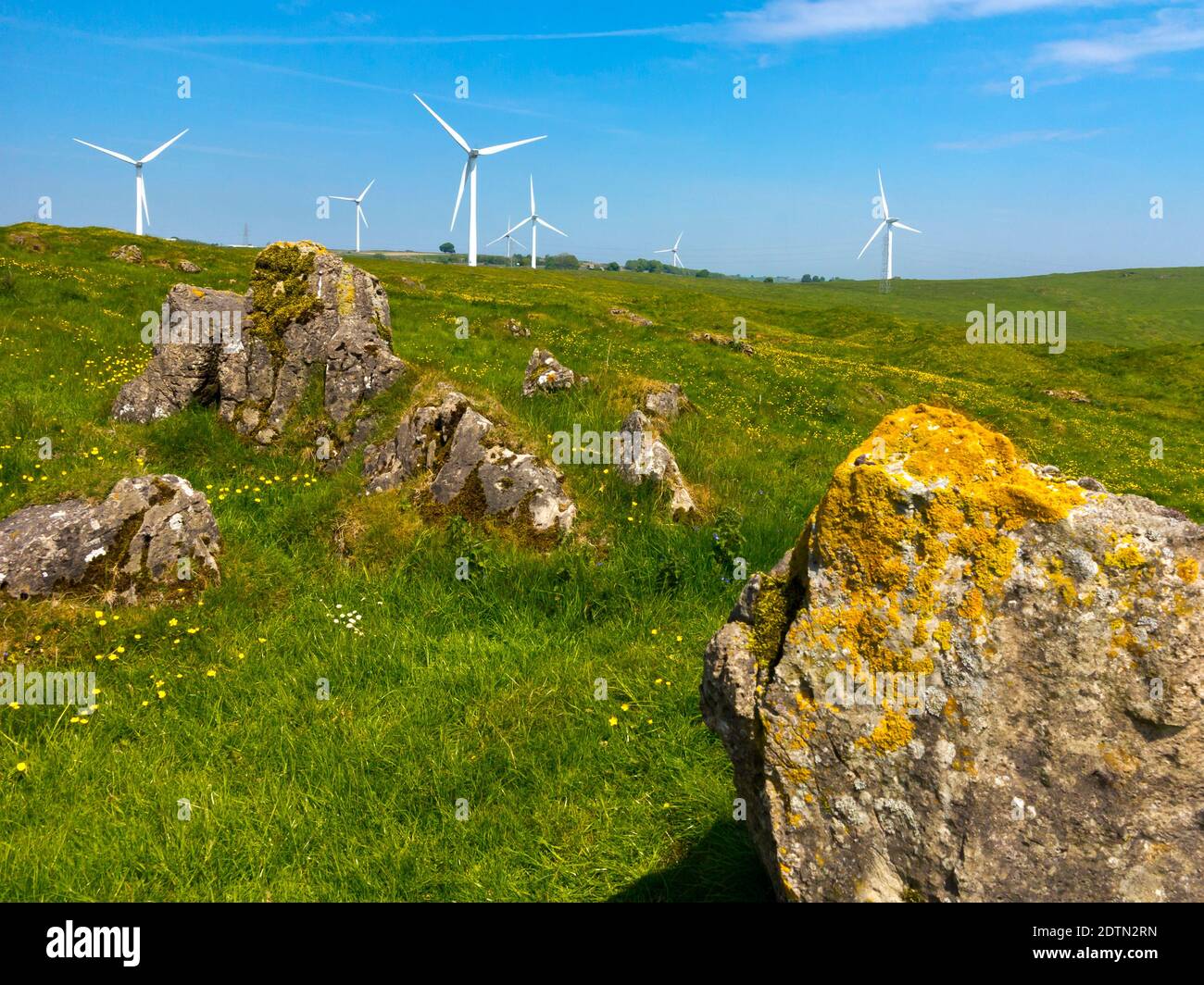 Kalksteinfelsen in der Landschaft auf Carsington Weiden in der Nähe von Brassington in der Derbyshire Dales England mit Windturbinen im Hintergrund. Stockfoto