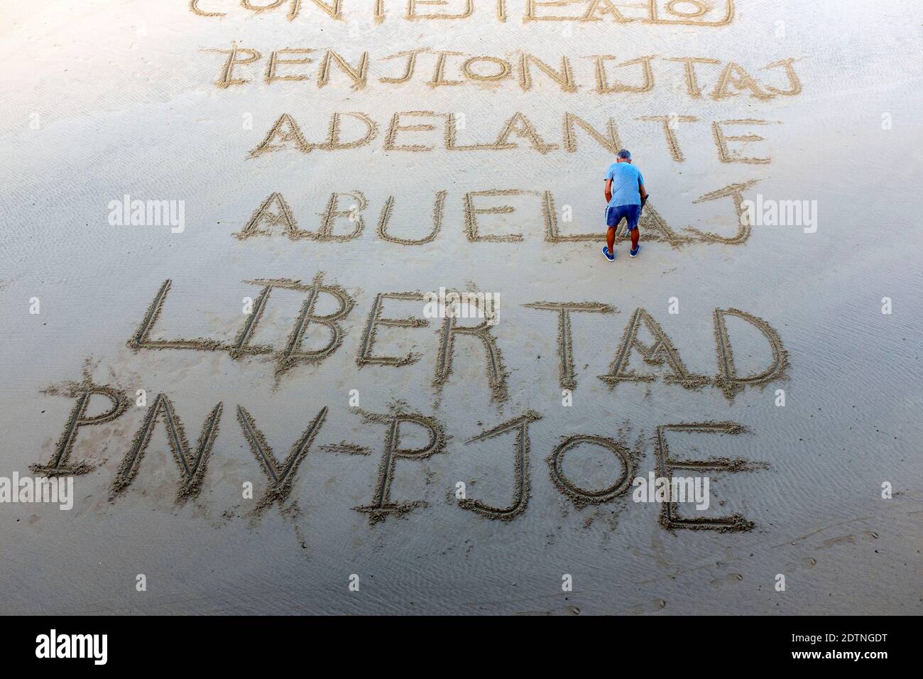 Spanien, das spanische Baskenland, Donostia, San Sebastian: Mann, der Worte auf dem Sand des Strandes von La Concha schreibt. Libertad, Freiheit, PNV - PSOE, Baskisch Stockfoto