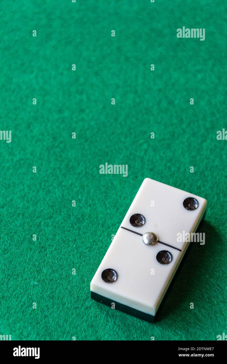 Draufsicht auf ein Stück Dominosteine, mit der Zahl zwei doppelt auf grüner Matte zu spielen, vertikal mit Kopierraum Stockfoto