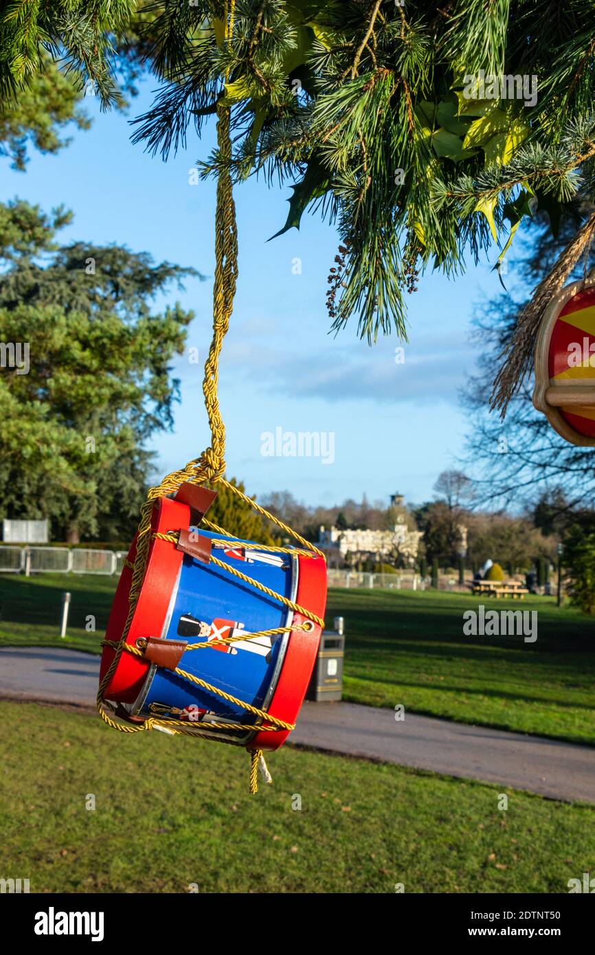 Festlich dekorierte Trommel hängt an einem Baumzweig in einem Park an einem hellen Tag mit einem malerischen Blick auf die Gebäude in Trentham Gardens, Stoke on Trent Stockfoto