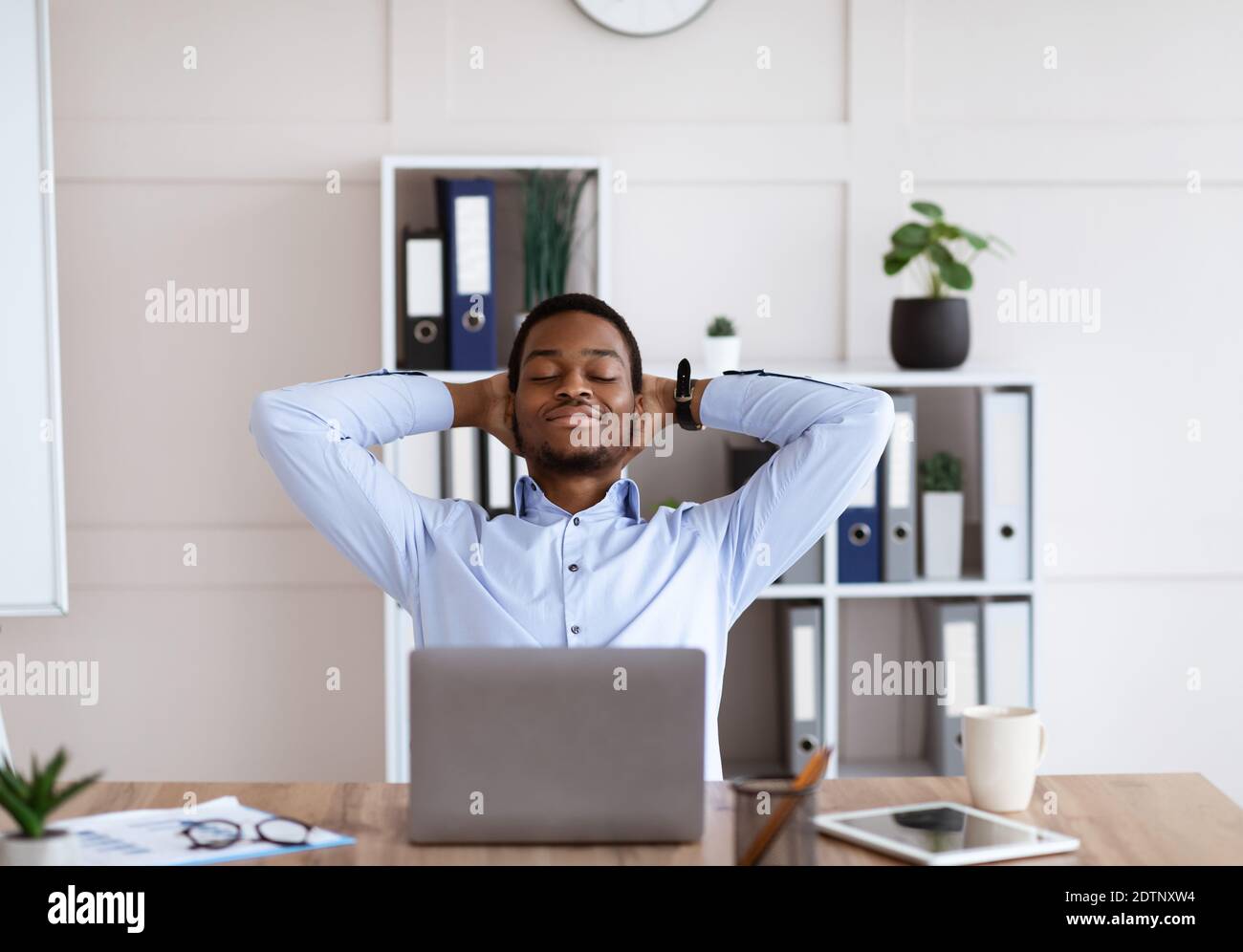 Zufriedener afroamerikanischer Geschäftsmann, der sich auf seinem Stuhl entspannt Stockfoto
