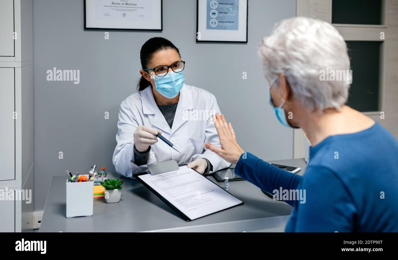 Weibliche Patientin, die sich weigert, die Einwilligungserklärung für den Coronavirus-Impfstoff zu unterzeichnen Stockfoto