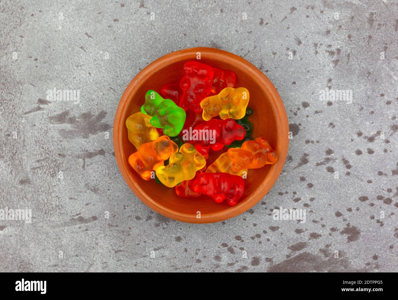Ansicht von oben auf einer Schüssel mit bunten Gummibären Zucker Bonbons auf einem grauen Hintergrund. Stockfoto