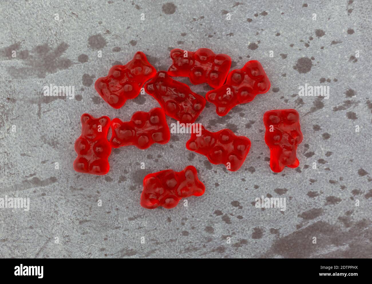 Ansicht von oben auf einem grau gesprenkelten Hintergrund einer Portion von bunten roten Gummibären Zuckerrüben. Stockfoto