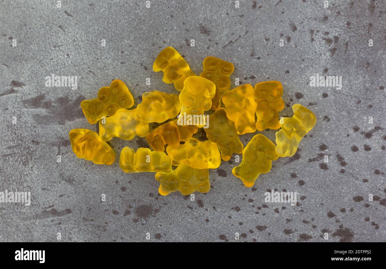 Ansicht von oben auf einem grau gesprenkelten Hintergrund einer Portion von bunten gelben Gummibären Zucker Bonbons. Stockfoto