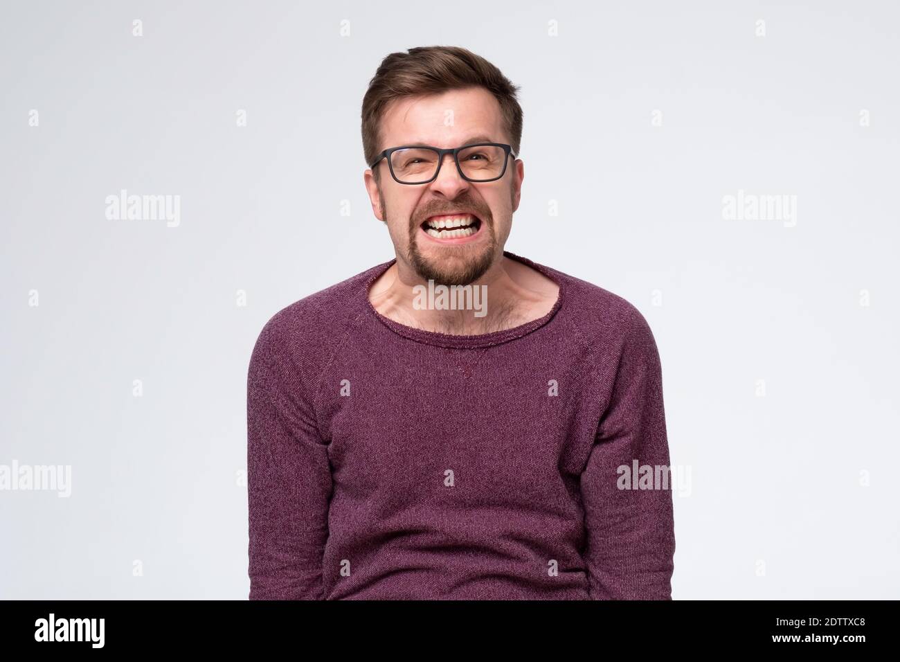 Wütend frustrierter Mann ist unzufrieden mit Service, gruseliges Grinsen auf seinem Gesicht. Studioaufnahme Stockfoto