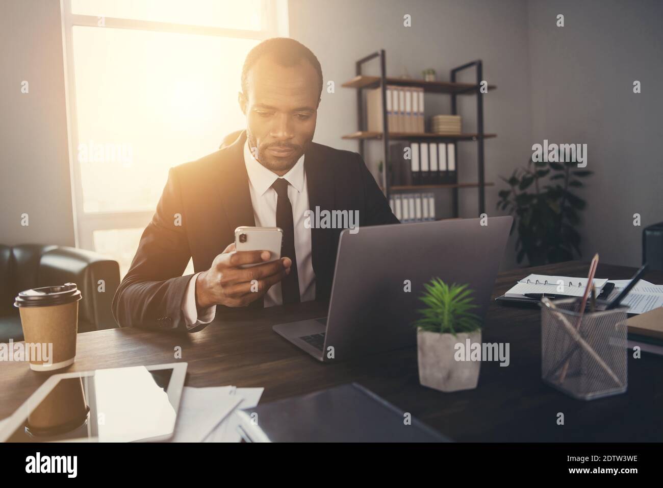Portrait von fokussierten nachdenklichen afro amerikanischen Mann Broker Rechtsanwalt verwenden Smartphone Chat mit Kunden Partner tragen Anzug Tuxedo in Arbeitsplatz Stockfoto