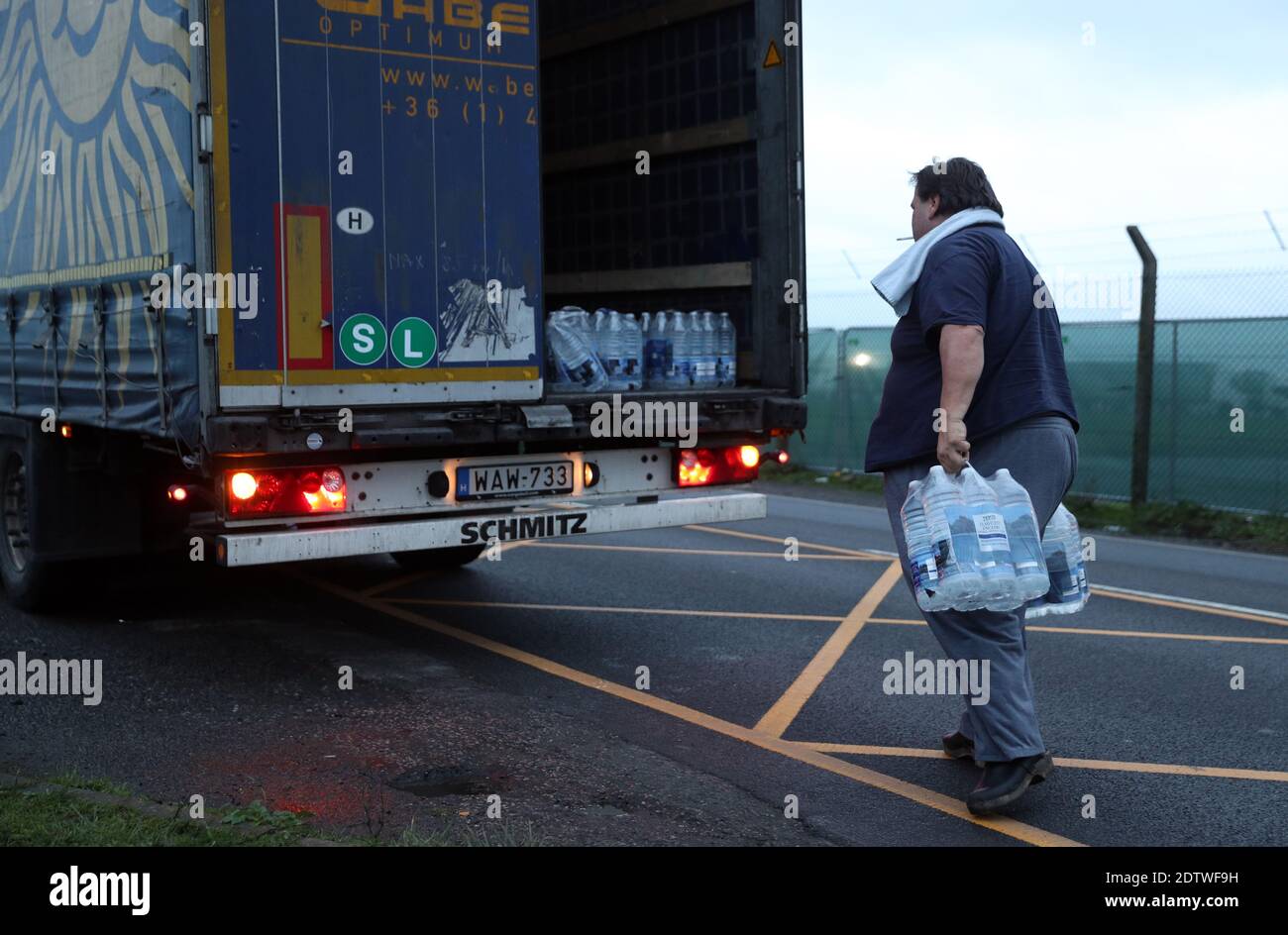 Ein Fahrer lädt Wasser, das ihm Laszlo Baliga (nicht abgebildet) gegeben hat, auf seinen Lastwagen, bevor er in den LKW-Park am Flughafen Manston, Kent, fährt. Nachdem Frankreich ein 48-Stunden-Einreiseverbot aus dem Vereinigten Königreich verhängt hatte, nachdem Bedenken wegen der Ausbreitung eines neuen Coronavirus-Stamms aufkam. Stockfoto