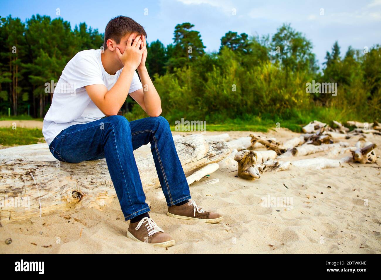 Trauriger junger Mann schließt das Gesicht mit den Händen Der Hintergrund der Natur Stockfoto