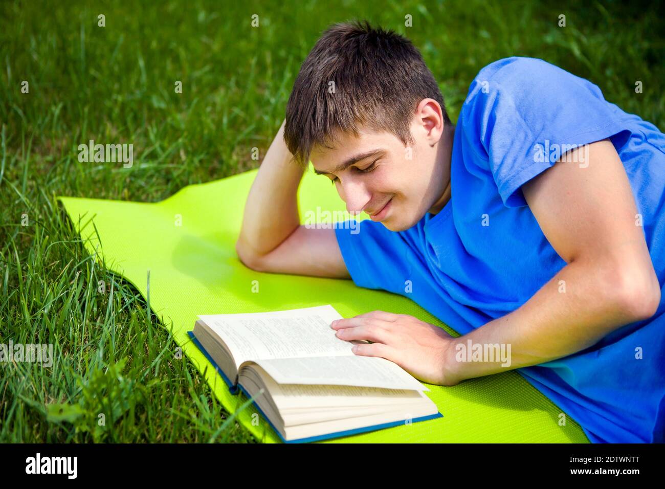 Glücklicher junger Mann las ein Buch über die Sommerwiese Stockfoto