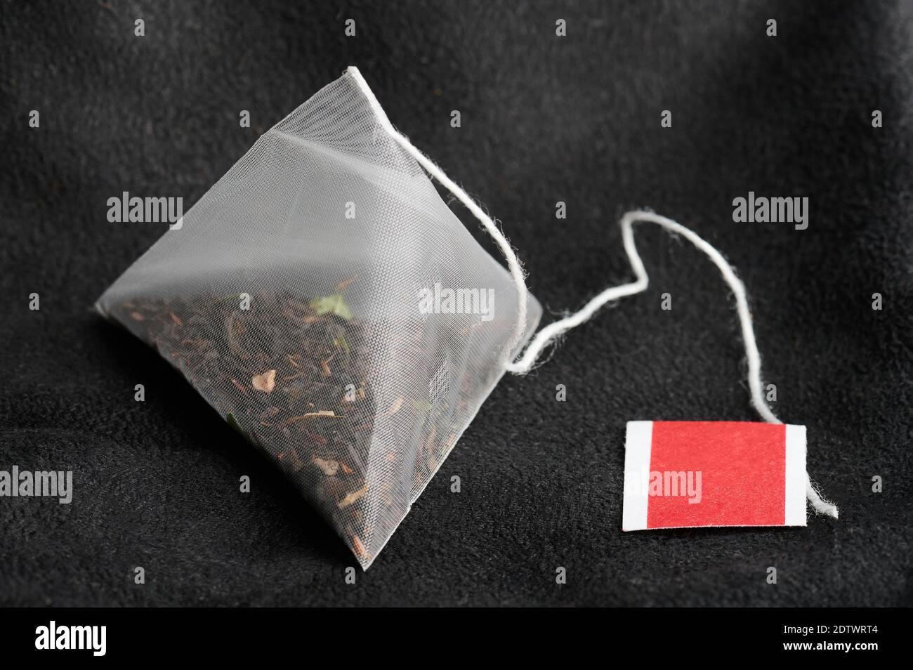 Reinigen Sie den neuen Teebeutel mit dem neuen Etikett auf einem weichen, dunklen Hintergrund Stockfoto