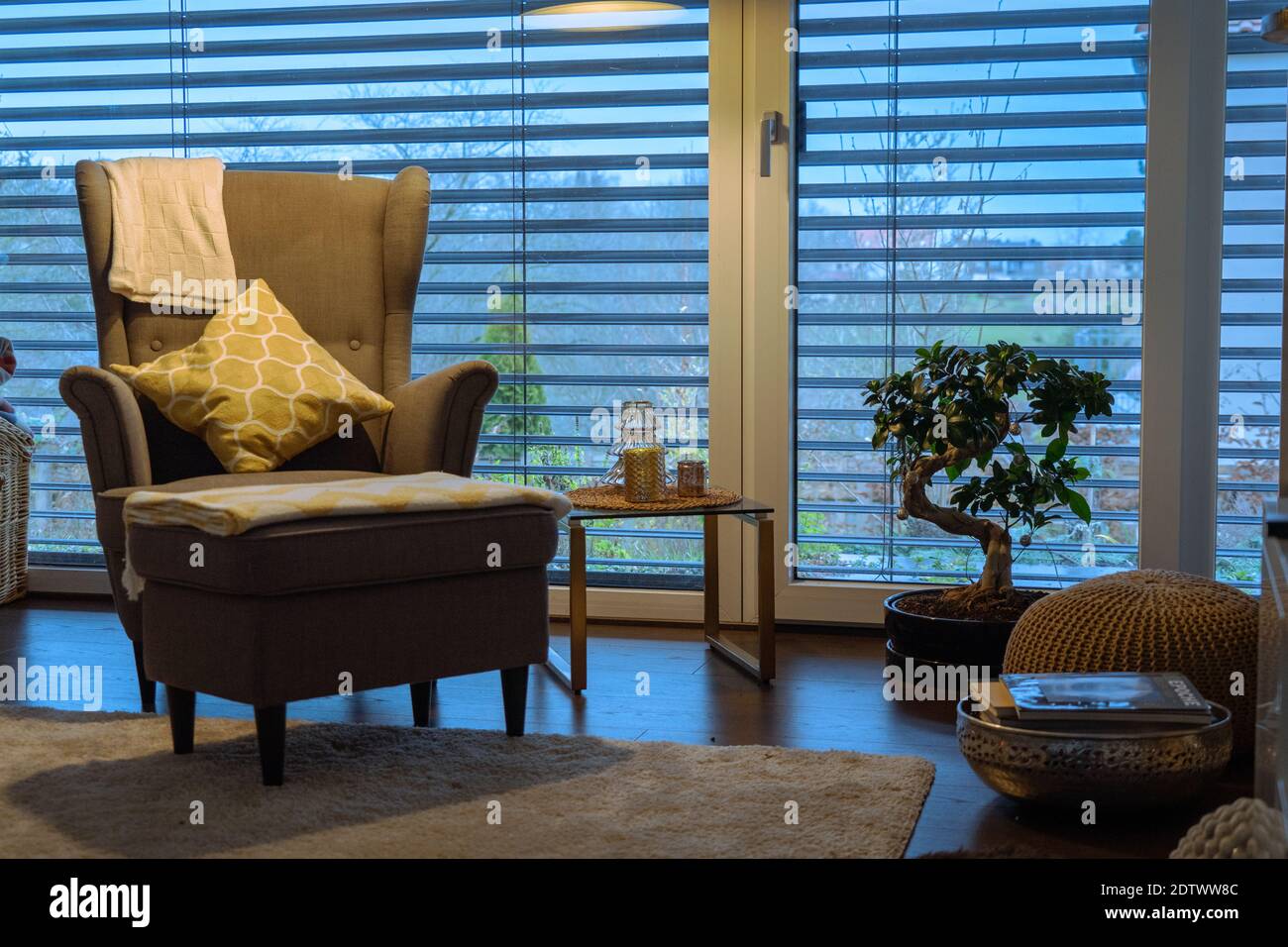 Modernes Wohnzimmer mit einem Lesesessel unter einem stilvollen Stehlampe und jalousien Stockfoto