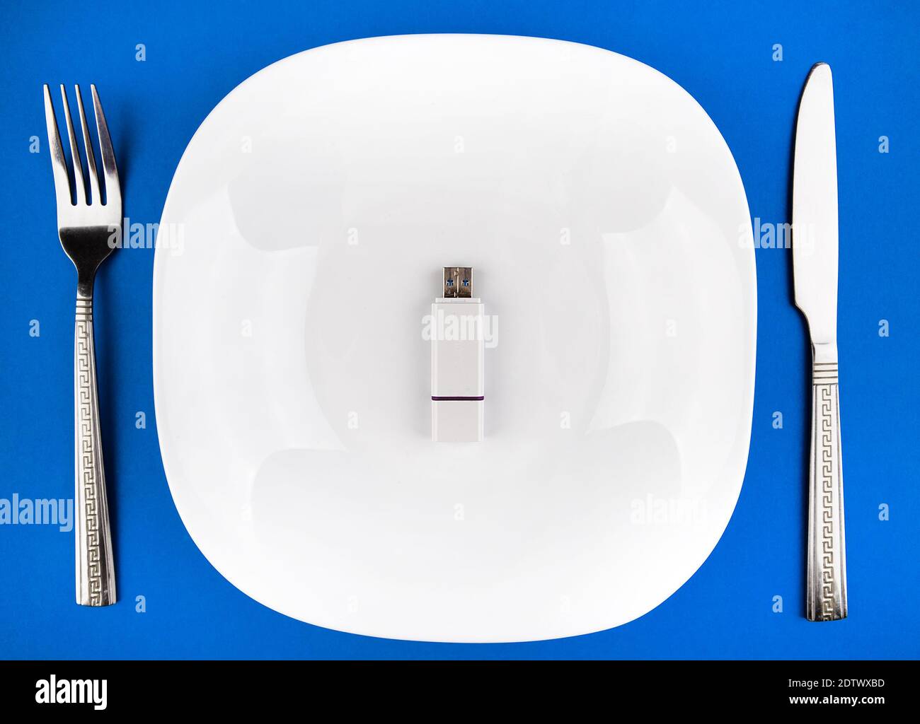 USB-Laufwerk in der Platte mit einem Besteck auf dem Blauer Papierhintergrund Stockfoto