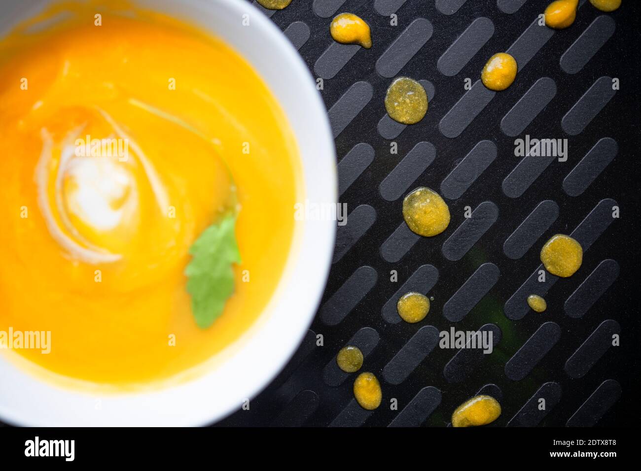 Gesunder Teller mit Squashsuppe auf einem schwarzen Tablett serviert Stockfoto