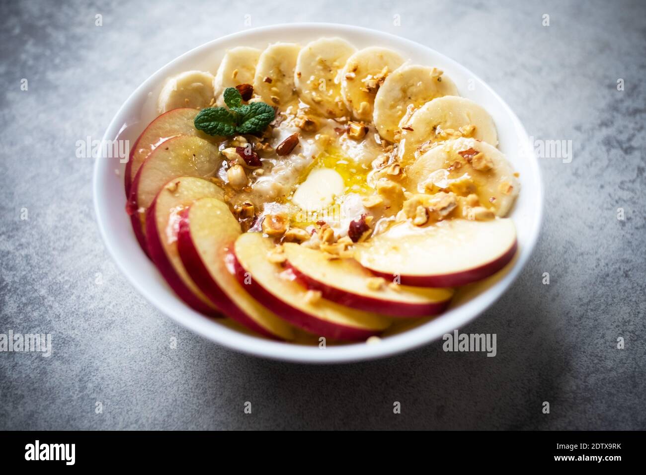 Haferflocken mit Banane, Nüsse, Apfel und Honig in einer weißen Schüssel Closep. Natürliche Gesundheit Diät Lebensmittel Stockfoto