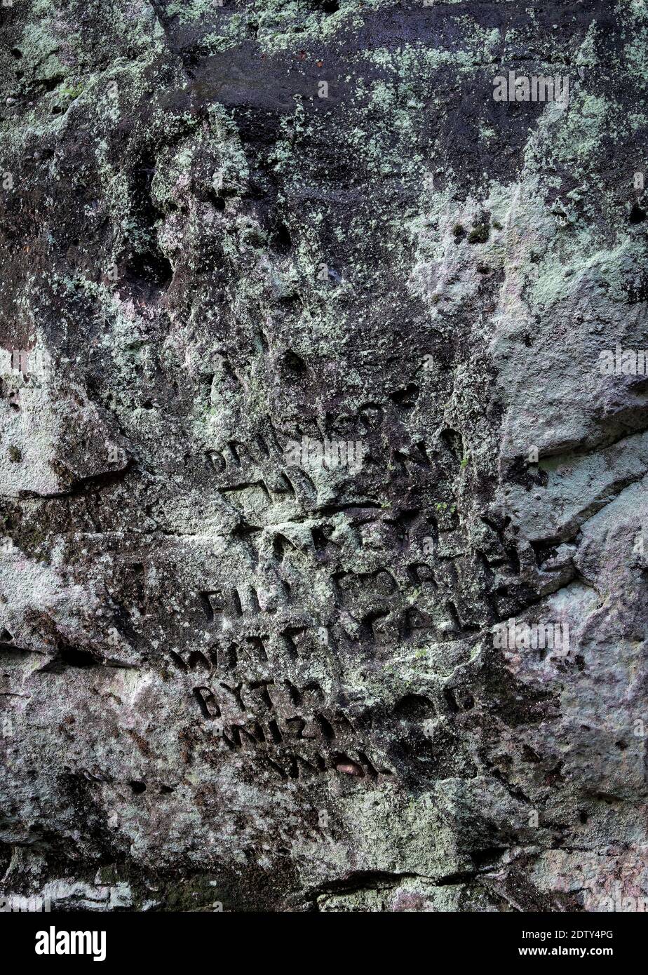 Inschrift & Gesicht in den Wizards Well Boulder, Alderley Edge, Cheshire, England, UK geschnitzt Stockfoto