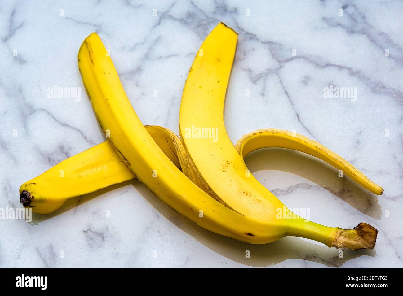 Gelbe Bananenschale über einem Marmorschneidebrett Stockfoto