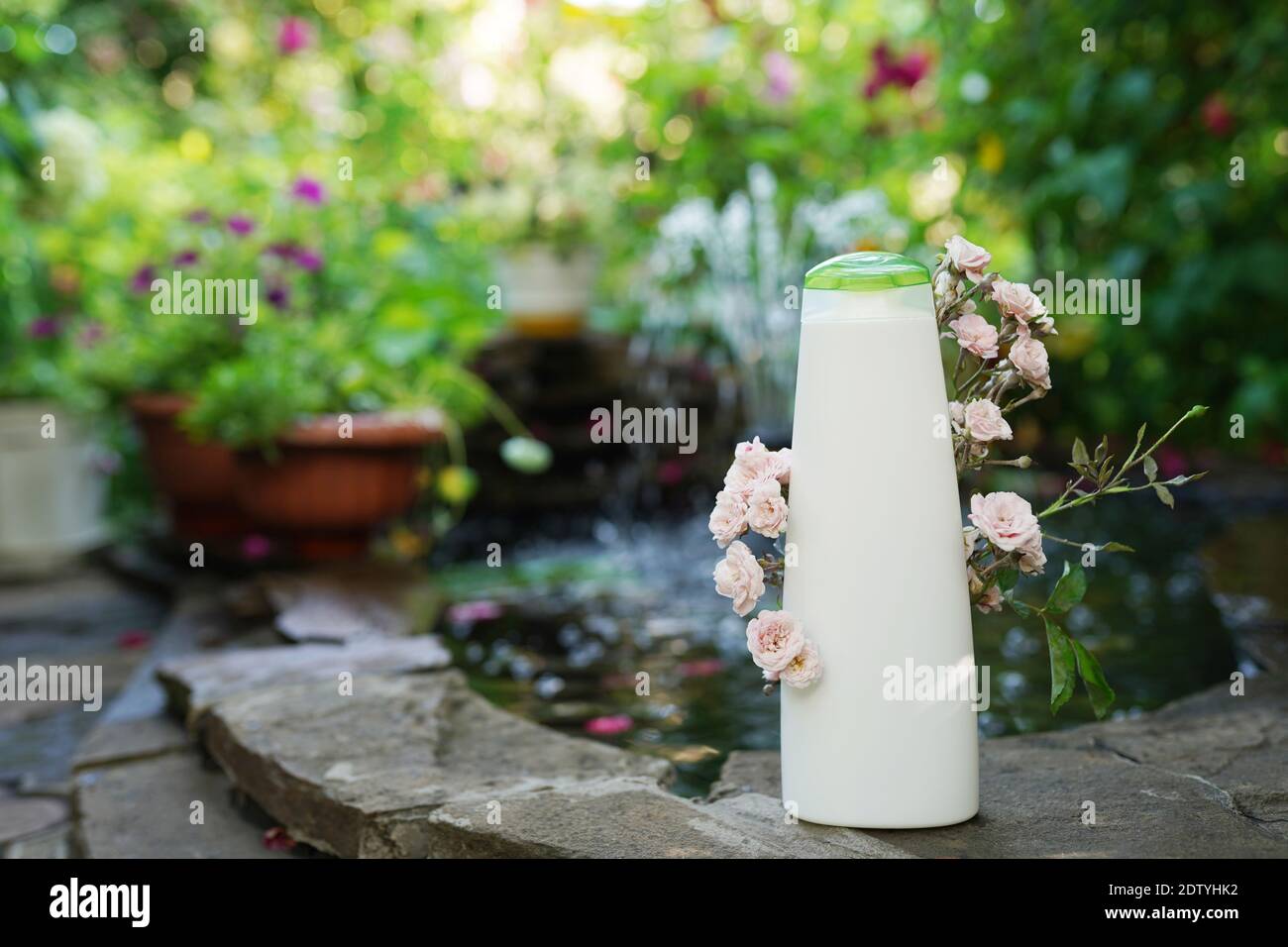 Bio Duschgel Flasche oder Shampoo-Flasche mit Zweig der Kleine rosa Rosen auf natürlichem Hintergrund.Körperpflege-Konzept Stockfoto